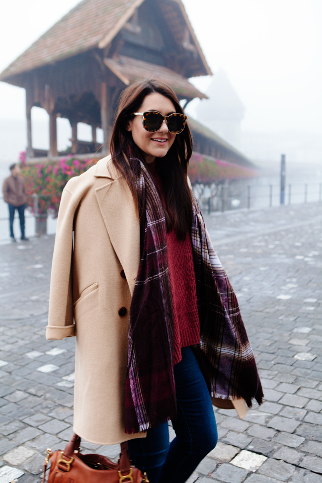 Burgundy sweater with plaid scarf and camel coat in Lucerne.