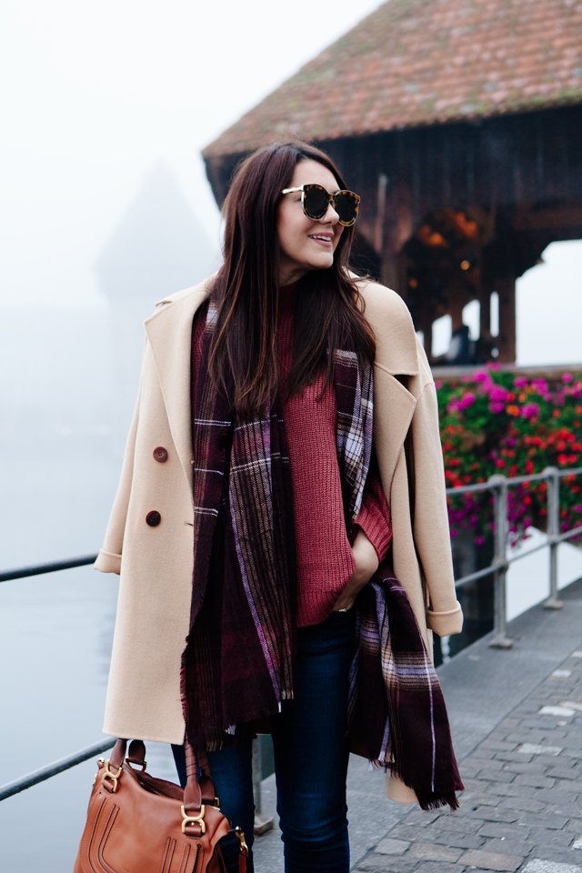 Burgundy sweater with plaid scarf and camel coat in Lucerne. 