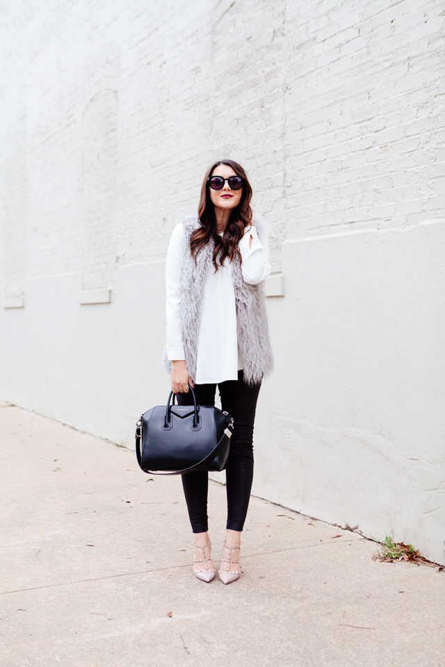 Grey faux fur vest with white blouse and black leggings outfit.