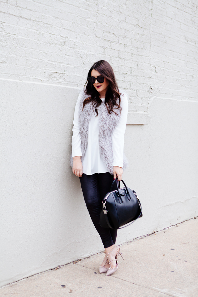 Grey faux fur vest with white blouse and black leggings outfit.