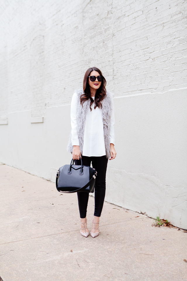 Grey faux fur vest with white blouse and black leggings outfit.