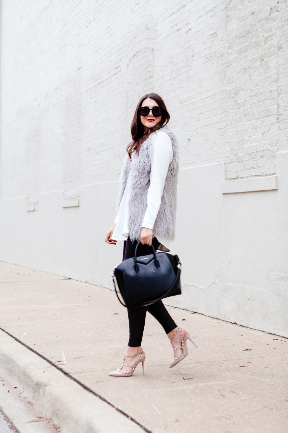 Grey faux fur vest with white blouse and black leggings outfit.