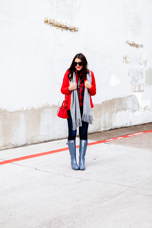 Bright red puffer jacket with layered plaid vest outfit.