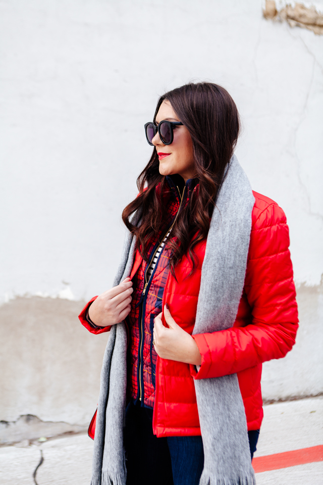 Bright red puffer jacket with layered plaid vest outfit.