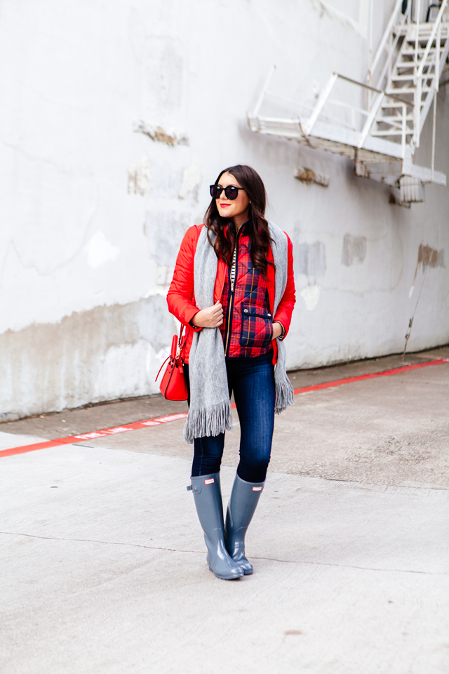 Bright red puffer jacket with layered plaid vest outfit.
