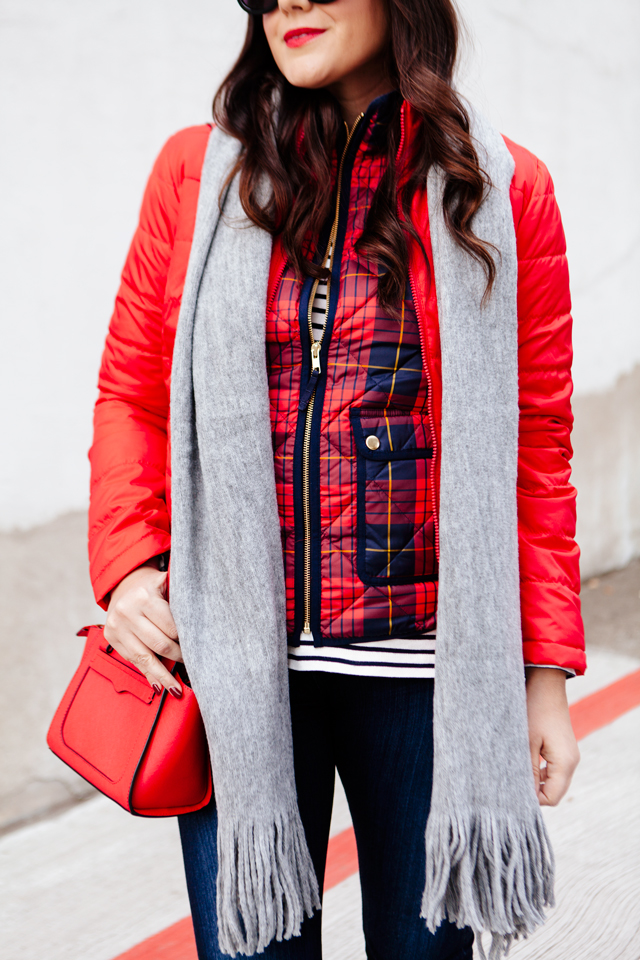 Bright red puffer jacket with layered plaid vest outfit.