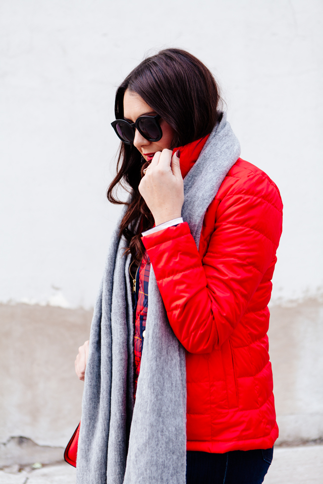 Bright red puffer jacket with layered plaid vest outfit.