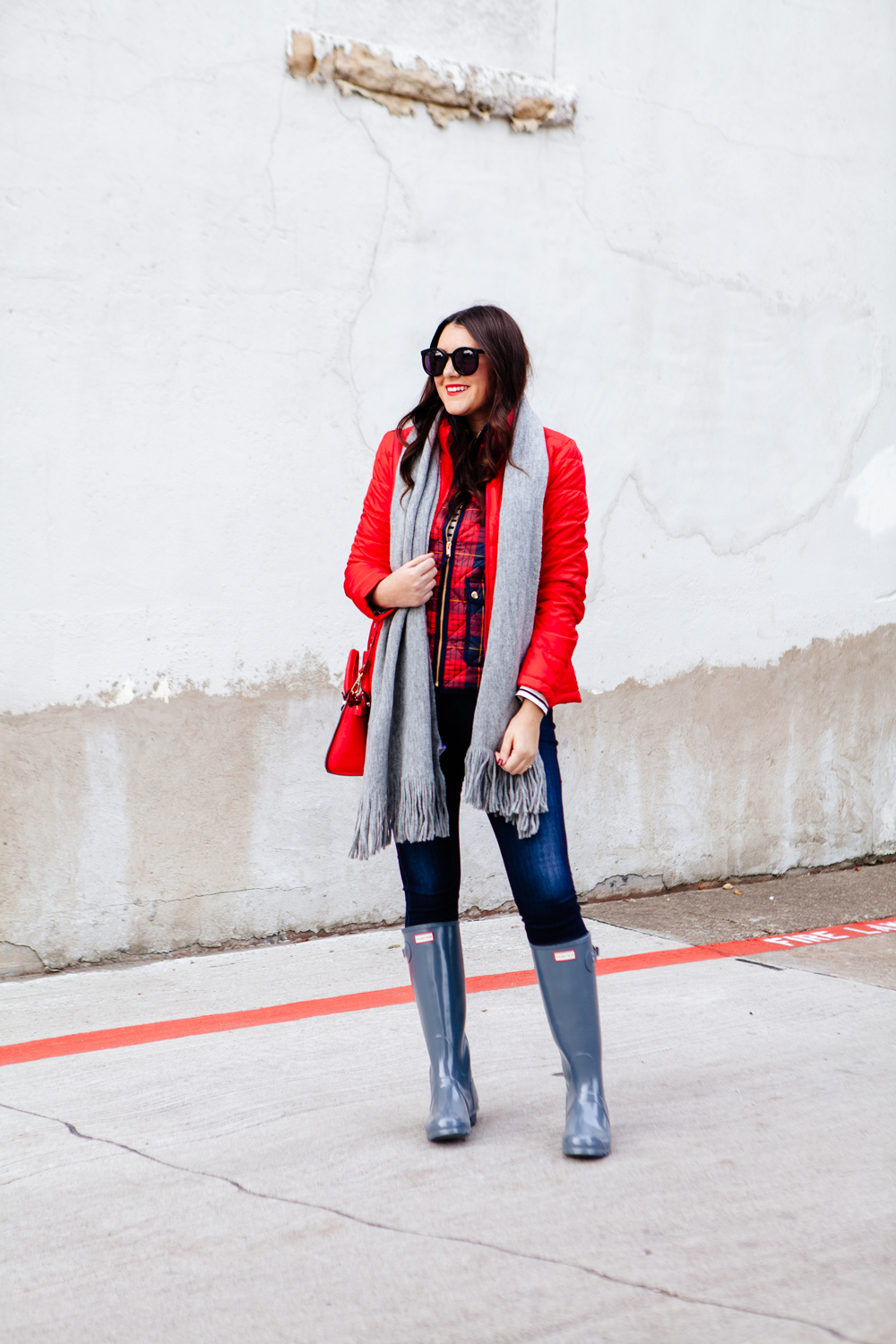 Bright red puffer jacket with layered plaid vest outfit.