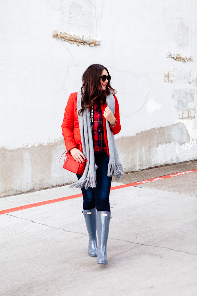 Bright red puffer jacket with layered plaid vest outfit.