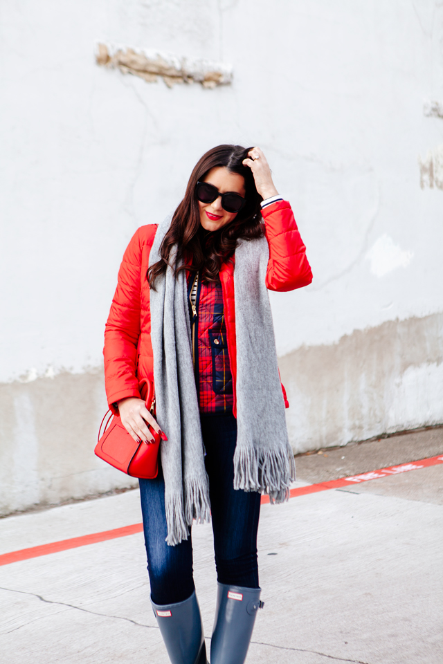 Bright red puffer jacket with layered plaid vest outfit.