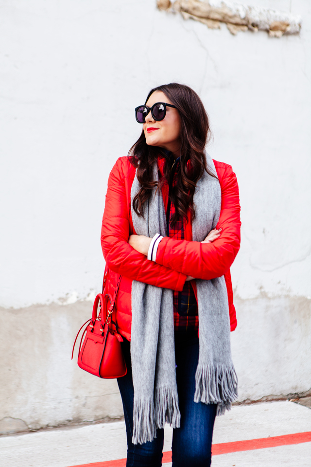 Bright red puffer jacket with layered plaid vest outfit.