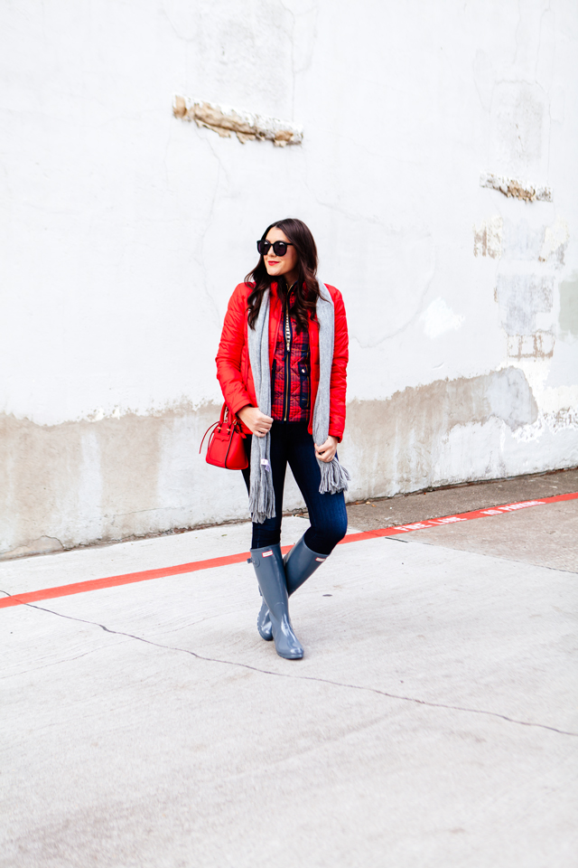 Bright red puffer jacket with layered plaid vest outfit.