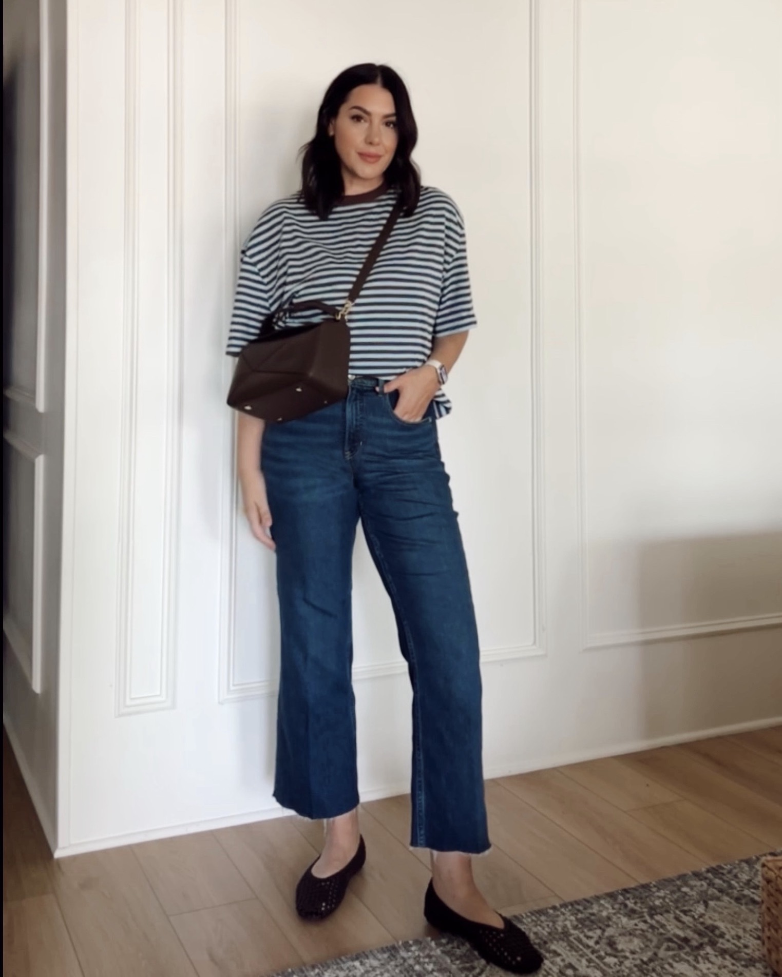 women in striped tee with denim jeans standing in a living room with white walls